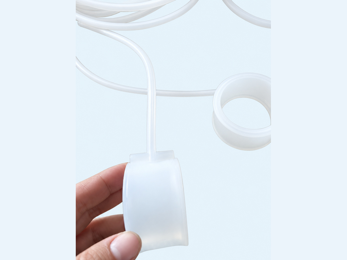 Close-up of a translucent ring-shaped component with a narrow clear tube, held by hand — Non-Implant Andrology Device Inflatable Seal